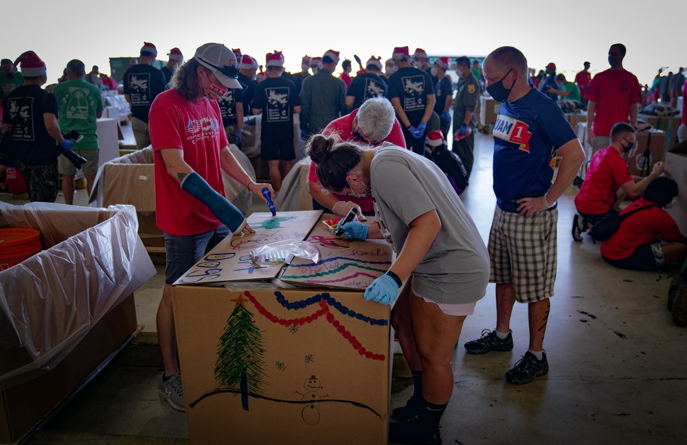 Volunteers pack donated goods into airdrop bundles during the 70th annual Operation Christmas Drop