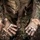U.S. service members train in French Desert Commando Course in Africa A person wearing a torn and dirty multicam/OCP camouflage uniform is displaying both hands palms-up toward the camera. Both hands are wrapped with worn, dirty athletic or medical bandaging tape, suggesting physical exertion or injury. The uniform shows significant wear, tears, and staining consistent with prolonged field use.