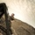 U.S. service members train in French Desert Commando Course in Africa Two individuals in military camouflage uniforms are engaged in a rope-climbing exercise on a metal training structure. One person is actively climbing the rope while the second person below is providing a boost by supporting the climber's feet. The setting appears to be an outdoor military obstacle course or training facility with a hillside visible in the background.
