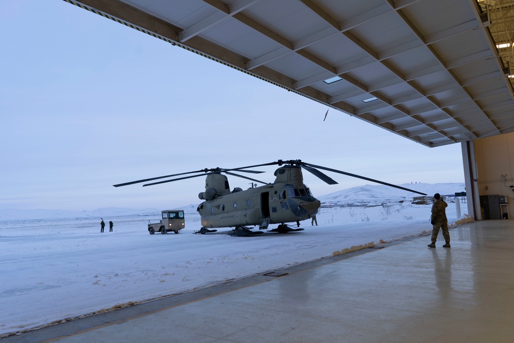 Alaka Army Natiolal Guard CH-47 Chinook helicopter is towed into a hangar.