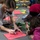 Celebrating the New Year at Task Force Liberty A group of people are gathered around a gray table engaged in a craft activity, writing 'Happy New Year!' on red paper. An adult woman in a striped shirt and black face mask is leaning over to help write on the paper, while a child in a magenta jacket and another person wearing a red head covering and face mask participate. The table is covered with colorful craft supplies including paper, markers, and decorative items.