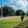 The Harry S. Truman Carrier Strike Group is on a scheduled deployment in the U.S. Sixth Fleet area of operations in support of naval operations to maintain maritime stability and security. A man walks solemnly along a row of grave markers in what appears to be a military or religious cemetery. A large concrete cross stands prominently on the left side of the grounds, backed by a stone wall and mature trees. The well-maintained green lawn and orderly grave markers suggest a formal memorial site.
