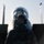 Day by Day with the 492nd Fighter Squadron A military ground crew member wearing camouflage uniform and hearing protection headset stands facing a military jet aircraft from the front. The image is taken from behind the personnel, creating a silhouette effect against a pale sky. The aircraft's nose cone and cockpit canopy are prominently visible in the background, slightly out of focus.