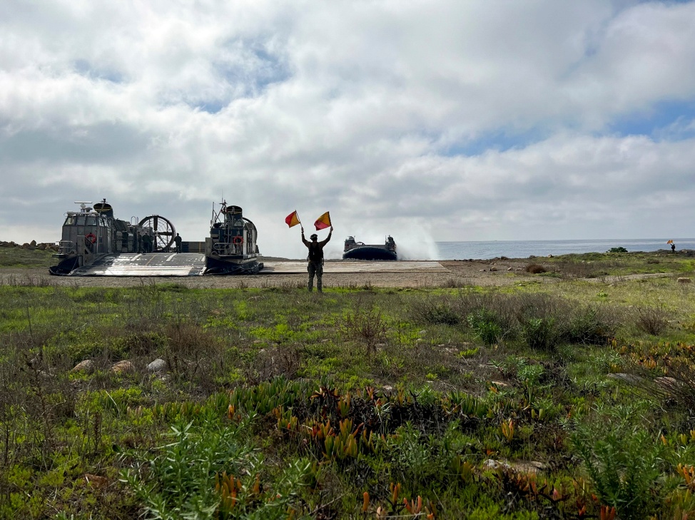 Sailor assigned to Beach Master Unit One guides a LCAC onto the beach