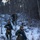 Three military personnel in MARPAT (Marine pattern) camouflage uniforms are conducting a patrol or field exercise through a snow-covered wooded area. They are armed with rifles and wearing cold-weather gear including watch caps and gloves. The scene appears to be a winter training exercise in a deciduous forest with bare trees.