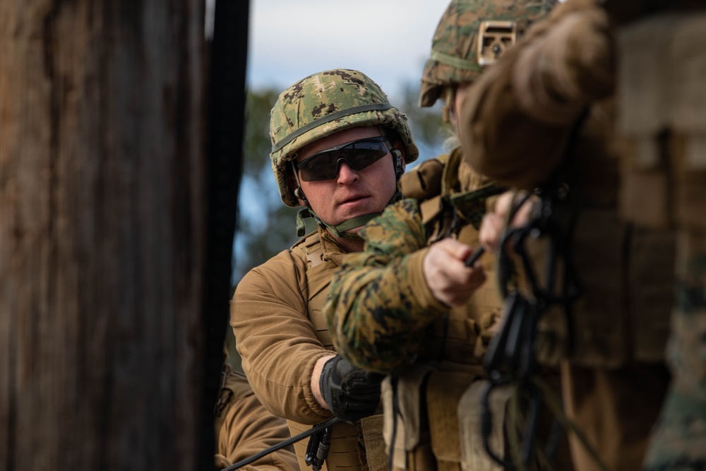 Marine engineers and Navy Seabees construct a one rope bridge during Winter Pioneer 22