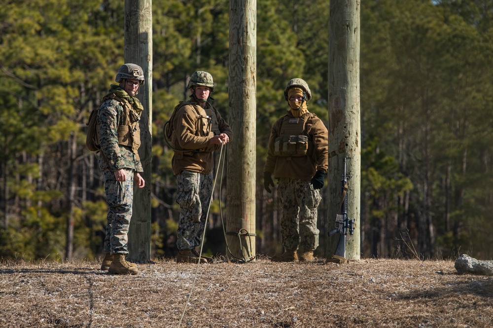 Marine engineers and Navy Seabees construct a one rope bridge during Winter Pioneer 22