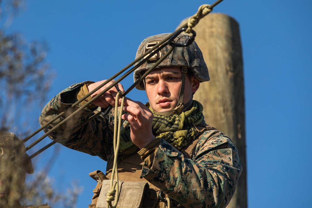 Marine engineers and Navy Seabees construct a one rope bridge during Winter Pioneer 22