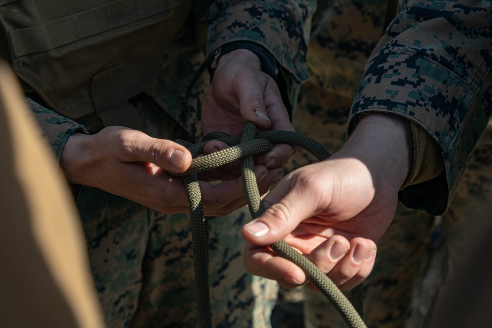 Marine engineers and Navy Seabees construct a one rope bridge during Winter Pioneer 22