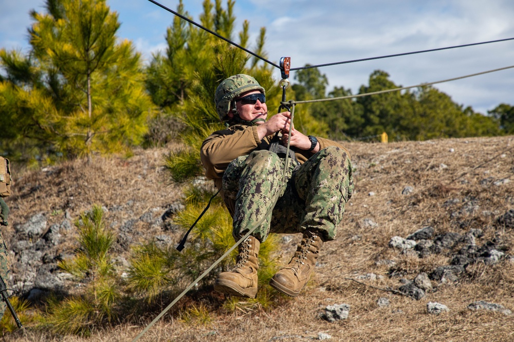 Marine engineers and Navy Seabees construct a one rope bridge during Winter Pioneer 22