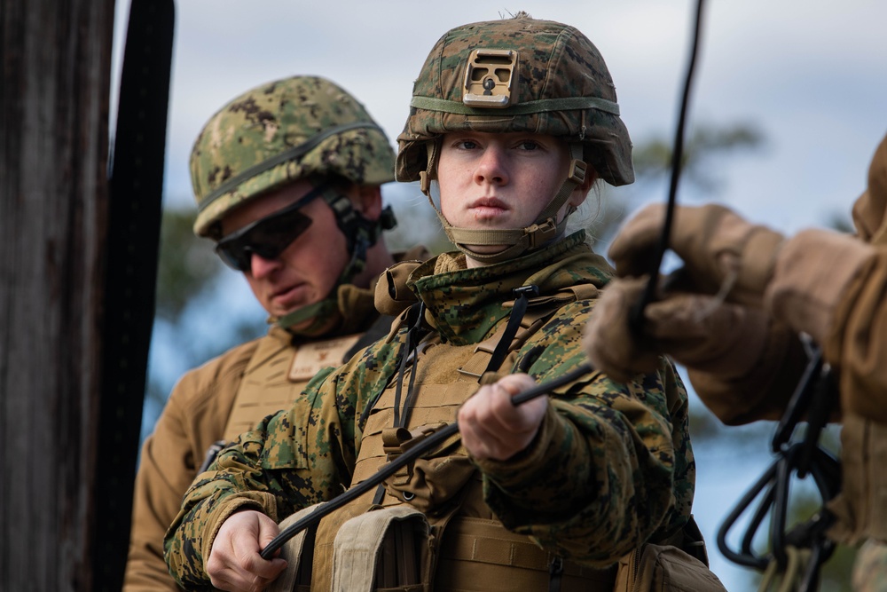 Marine engineers and Navy Seabees construct a one rope bridge during Winter Pioneer 22