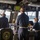 The image shows the bridge of the USS Milwaukee (LCS-5), a U.S. Navy Littoral Combat Ship, with several crew members at their stations. Personnel in Navy working uniforms are manning navigation and control consoles while the ship appears to be underway in a coastal or harbor environment. The scene captures routine bridge operations with multiple sailors monitoring equipment and looking out toward the water.