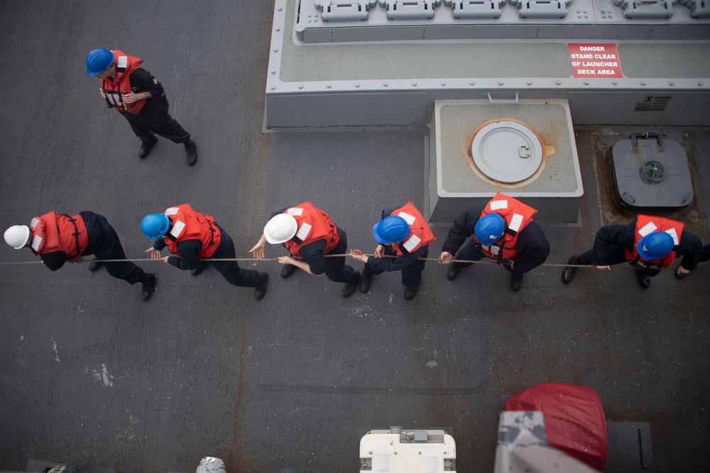 Sailors pull in lines during underway replenishment