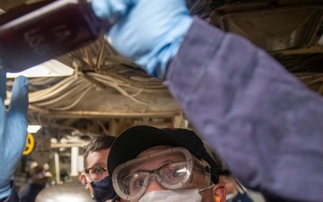 Damage Controlman 3rd Class Landon Helton, from Quilan, Texas, takes an oil sample