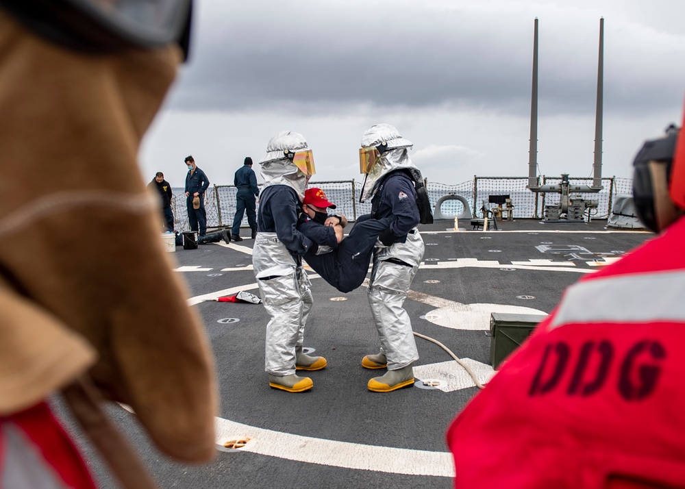 Sailors perform an emergency evacuation during a firefighting drill