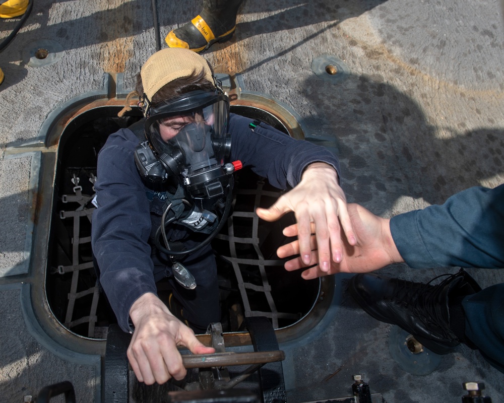 Machinery Repairman 3rd Class Landon Spencer, from Houston, Texas, exits a hatch during a toxic gas drill