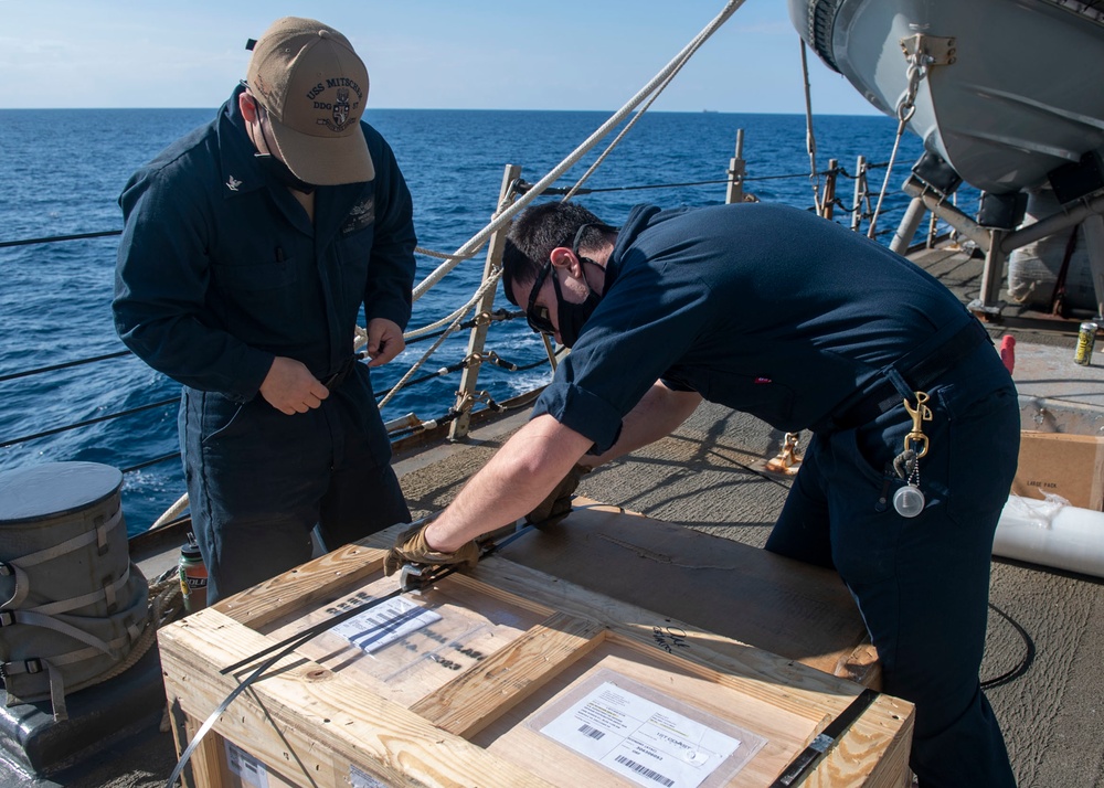 Logistics Specialist 3rd Class Amadeus Maestas (left), from Dallas, Texas, and Logistics Specialist 2nd Class Alexander Knaras (right), from Salt Lake City, Utah, clip binding straps to stores