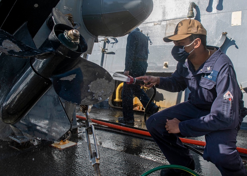 Machinist Mate 3rd Class Andre Haldane, from Philadelphia, Pa., washes the engine of a ridged-hull inflatable boat