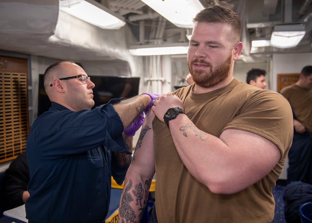 Hospital Corpsman 2nd Class Chase Correa (left), from Rochester, N.Y., administers a COVID-19 booster to Sonar Technician (Surface) 2nd Class Jesse Elmore (right), from Austin, Texas