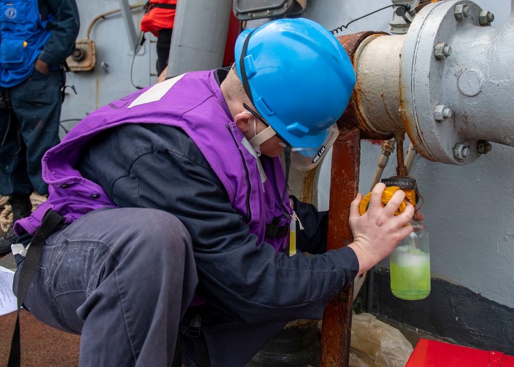 A Sailor takes a sample of F-76 fuel aboard Arleigh Burke-class guided-missile destroyer USS Mitscher (DDG 57) during a replenishment-at-sea