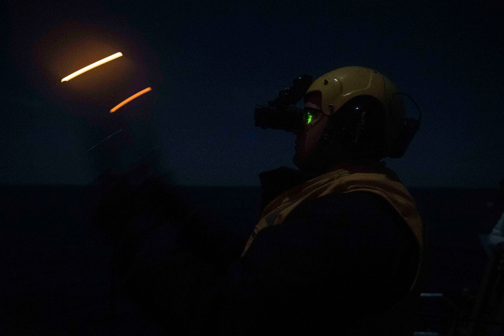 Sailor signals to aircraft aboard USS Gonzalez.