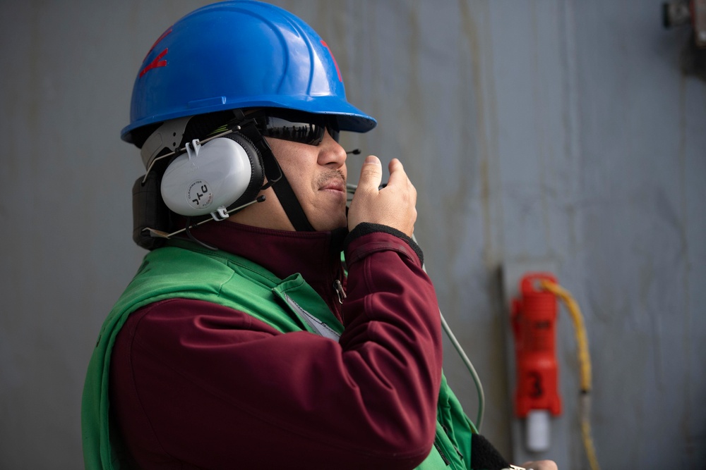 Sailor communicates through sound powered telephone during a replenishment-at-sea.