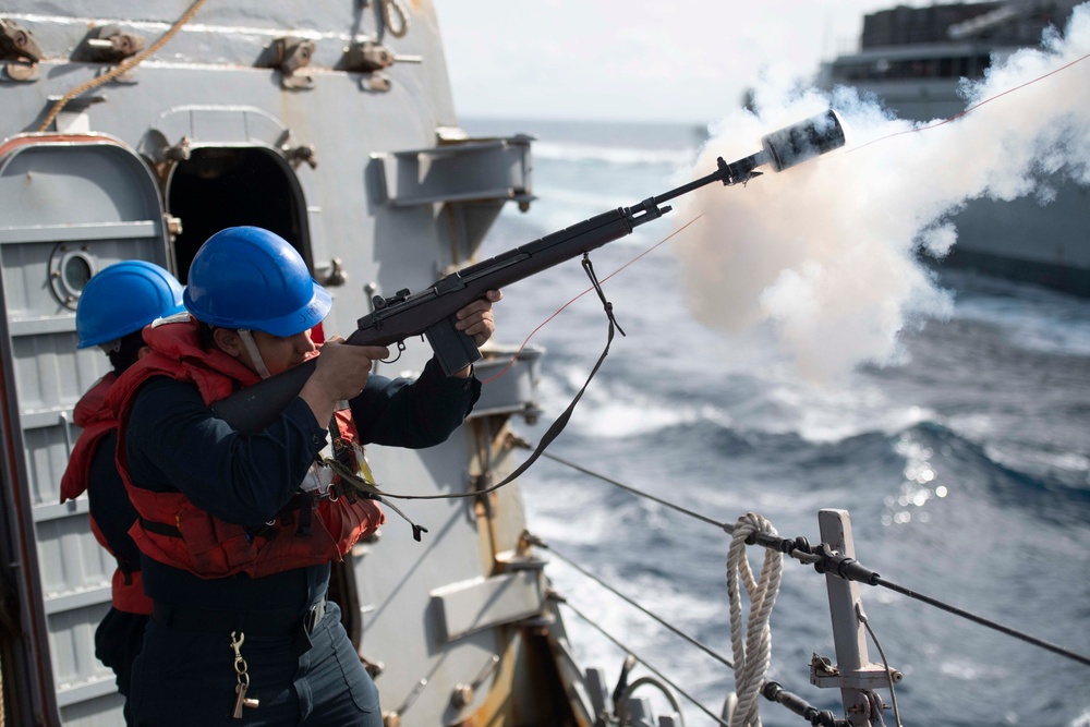 Sailor fires shot line during a replenishment-at-sea.