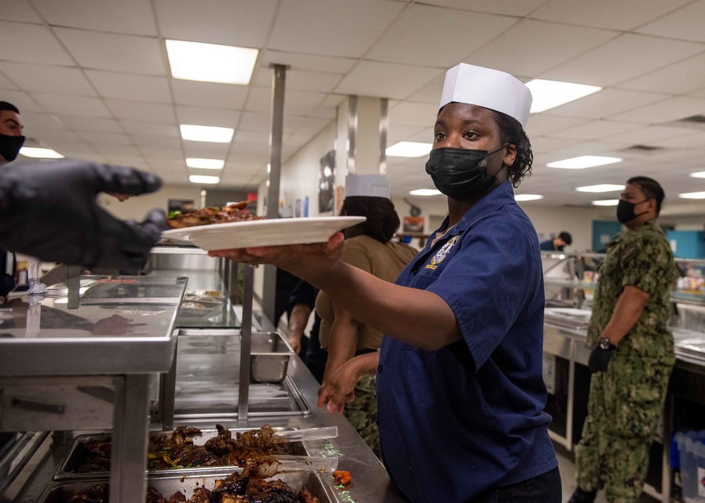 U.S. Navy Culinary Specialist Jenae Williams, from Williamsburg, Virginia, serves food at the Black History Month commemorative lunch