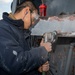 Seaman Tuo Li, from Warbin, China, removes paint with a pneumatic grinder