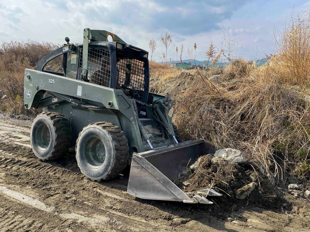 NMCB THREE Detail Iwakuni Seabee clears debris with 325 John Deer Skid Steer