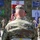 Kentucky Guardsmen Assume Authority A military ceremony is taking place outdoors, featuring soldiers in US Army MultiCam (OCP) uniforms. The central figure, identified by name tape as 'HOPKINS,' is viewed from behind facing a formation of soldiers. Multiple national and organizational flags are displayed in the background, indicating a multinational military event.