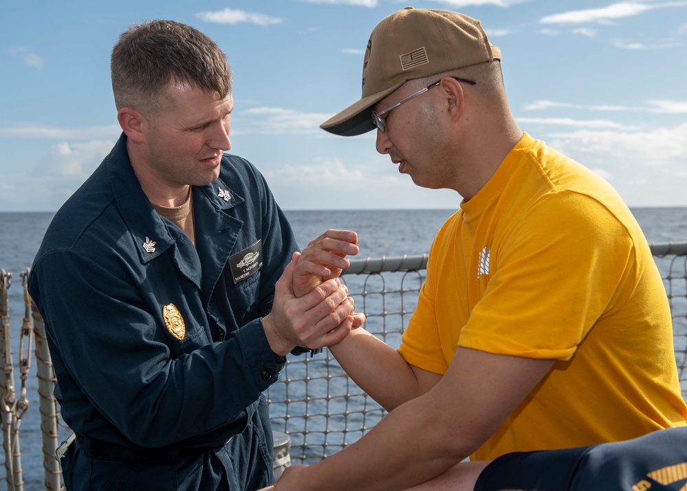 Master-at-Arms 1st Class Trenton McKibben (left), from Orlando, Fla., teaches takedown techniques with Fire Controlman (AEGIS) 3rd Class Liangchao Ou (right), from San Diego, Calif., during Security Reaction Force – Basic training course