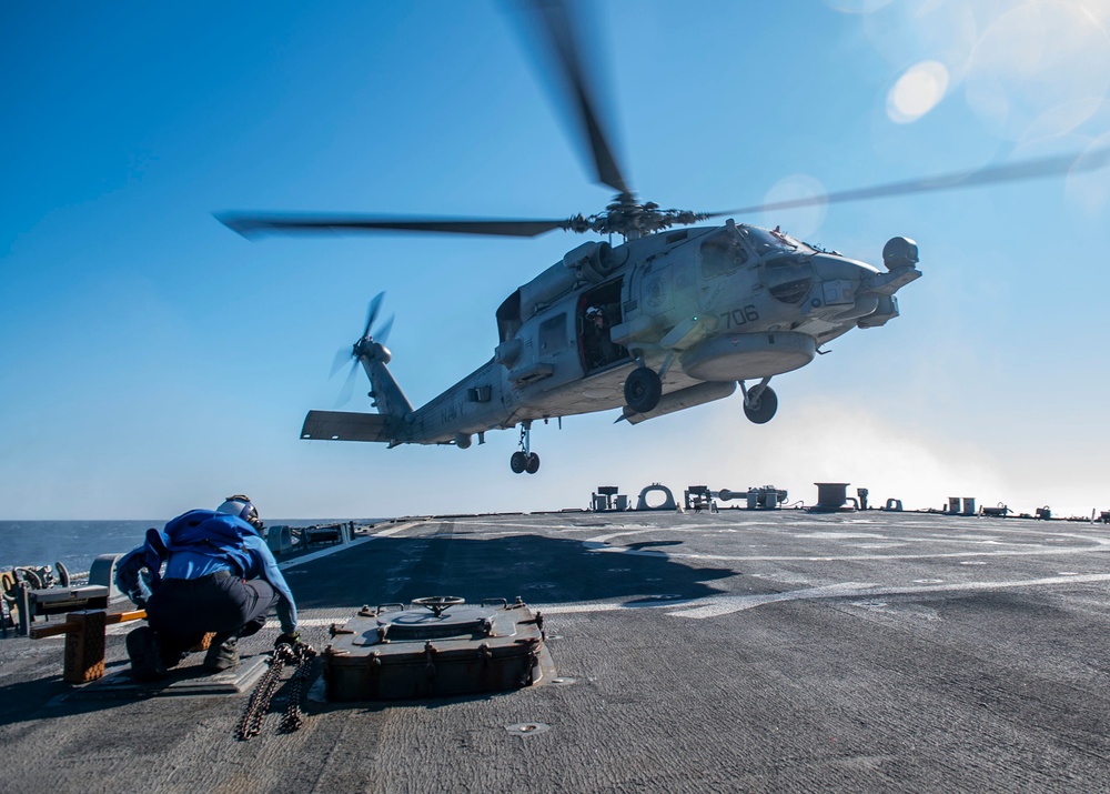 Boatswain’s Mate 3rd Class Brian Bisarz, from Long Island, N.Y., prepares to chock and chain a MH-60R Sea Hawk helicopter