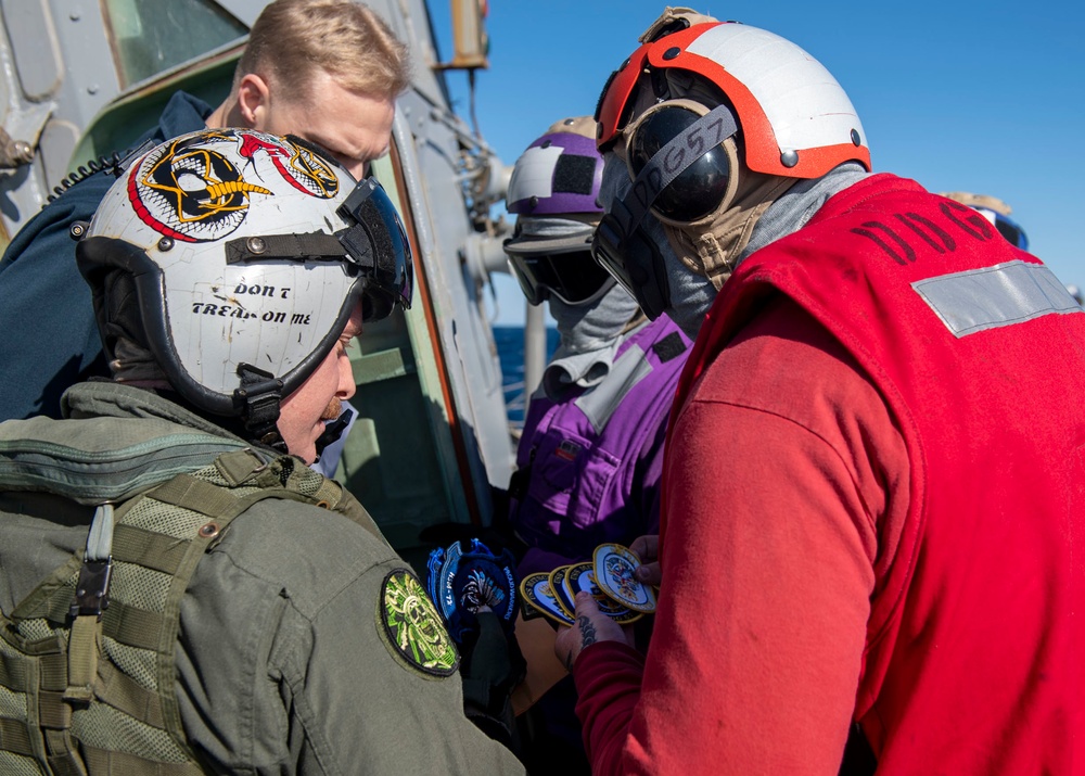 Logistics Specialist 2nd Class Nicholas Forbes (right), from Norfolk, Va., exchanges command patches with an aircrewman