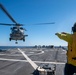 Boatswain’s Mate 3rd Class Tra’shaun Cooper, from Homestead, Texas, directs a MH-60R Sea Hawk helicopter