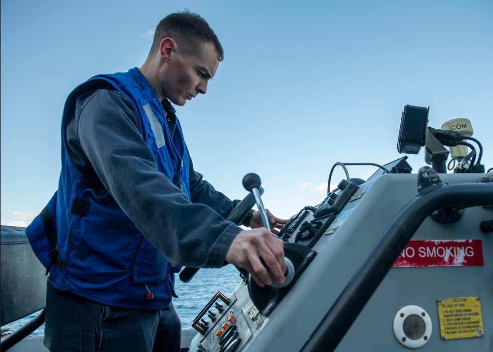 Machinist Mate 1st Class Kenneth Peterson, from Houston, Texas, conducts a maintenance on a ridged-hull inflatable boat