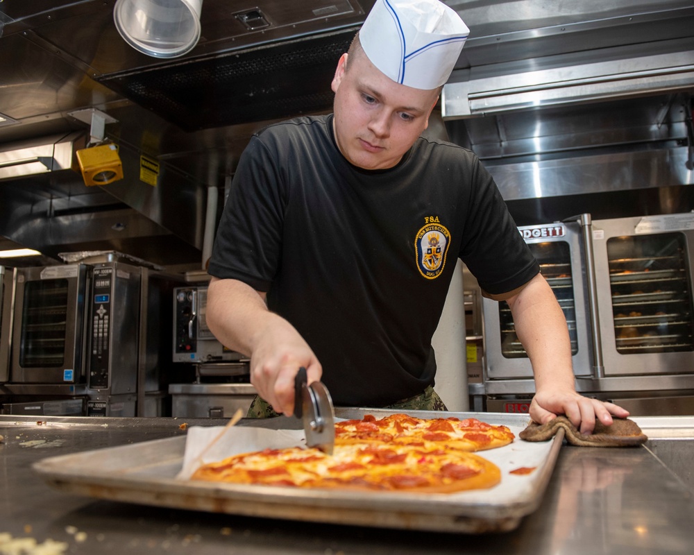 Professional Apprenticeship Career Tract (PACT) Seaman Kyle Stone, from Paducah, Ky., cuts pizza to serve the crew in the galley