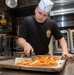 Professional Apprenticeship Career Tract (PACT) Seaman Kyle Stone, from Paducah, Ky., cuts pizza to serve the crew in the galley