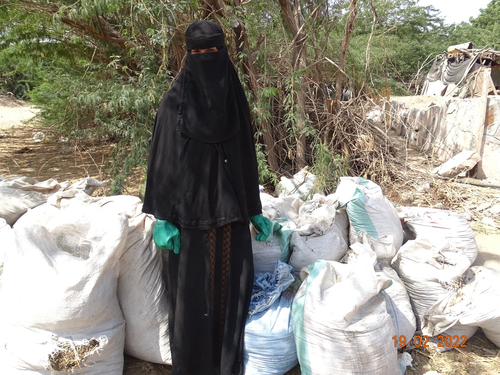 Etimad Saied Mohamed Saied stands among bags of fermented compost, which she sells to local farmers to support her family of six, in the Al Howtta District of Lahj Governorate, Yemen, in February 2022.