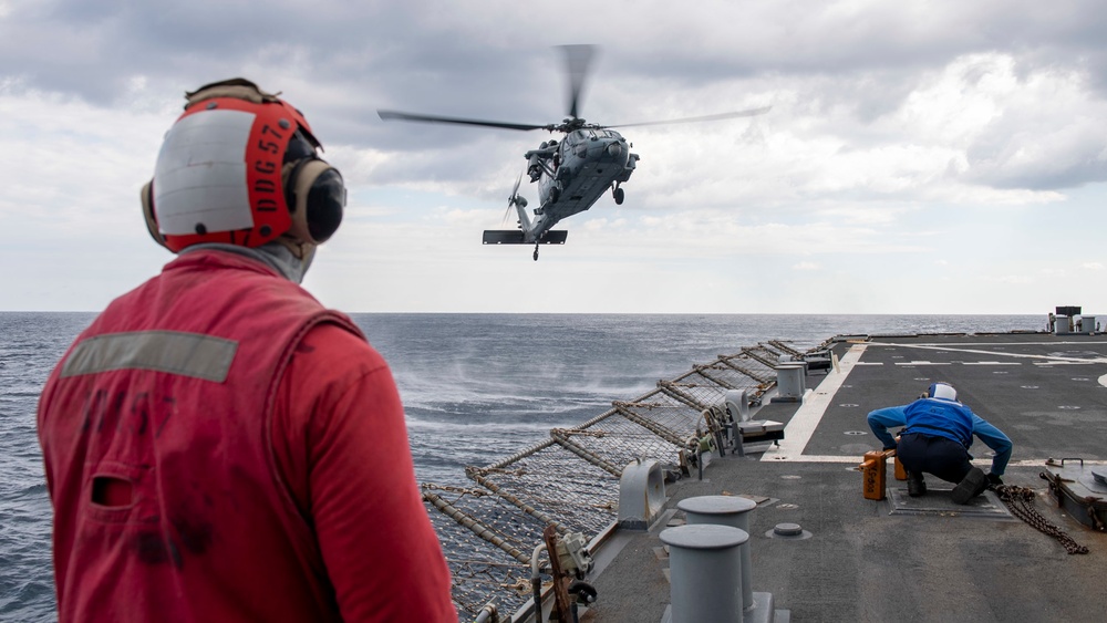 Sailors aboard Arleigh Burke-class guided-missile destroyer USS Mitscher (DDG 57) prepare to receive an MH-60S Sea Hawk helicopter assigned to the “Dragon Slayers” of Helicopter Sea Combat Squadron (HSC) 11