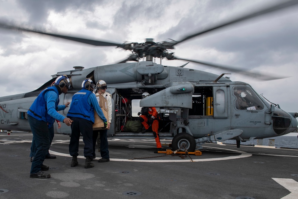 Sailors aboard Arleigh Burke-class guided-missile destroyer USS Mitscher (DDG 57) conduct a parts transfer with an MH-60S Sea Hawk helicopter assigned to the “Dragon Slayers” of Helicopter Sea Combat Squadron (HSC) 11
