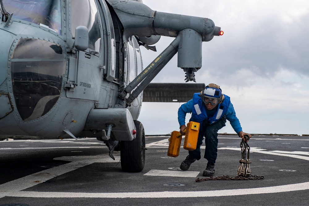 Boatswain’s Mate 3rd Class Isaiah Strickland, from Galesburg, Ill., removes chock and chains from an MH-60S Sea Hawk helicopter