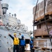 Boatswain’s Mate 2nd Class Justin Bauer, from Fredrick, Colo., signals to lower the pad eye winch