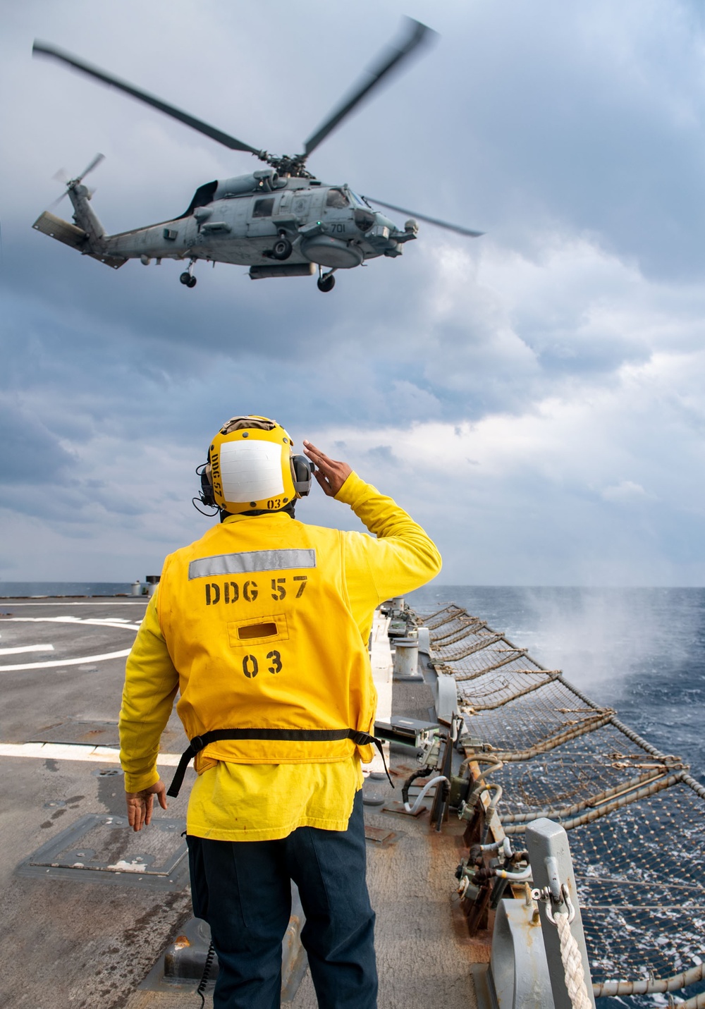 Boatswain’s Mate 3rd Class Tra’shaun Cooper, from Homestead, Texas, salutes the pilots of an MH-60R Sea Hawk helicopter assigned to the “Proud Warriors” of Helicopter Maritime Strike Squadron (HSM) 72