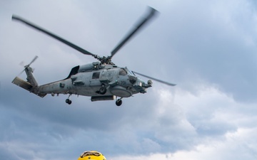 Boatswain’s Mate 3rd Class Tra’shaun Cooper, from Homestead, Texas, salutes the pilots of an MH-60R Sea Hawk helicopter assigned to the “Proud Warriors” of Helicopter Maritime Strike Squadron (HSM) 72