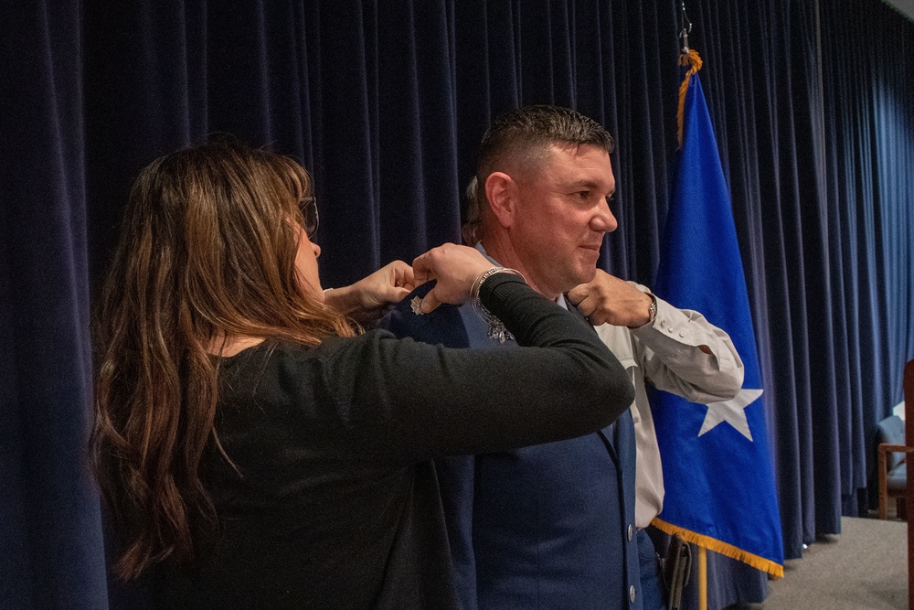 THE PINNING: Maj. Robert Kolvet's wife and father pin his new Lieutenant Colonel rank on his uniforn during Kolvet's promotion ceremony