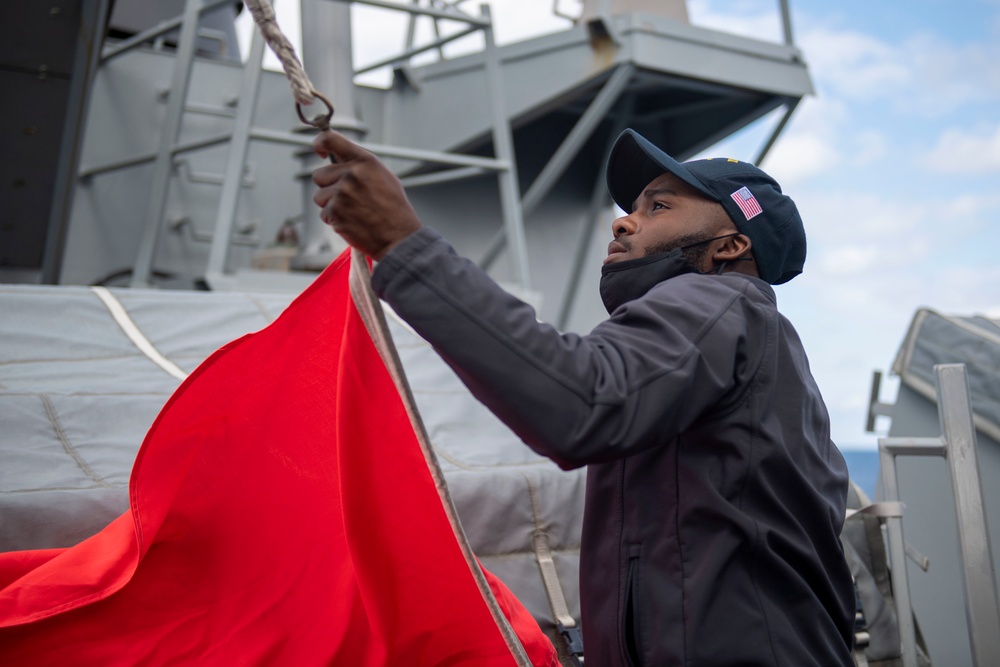 Quartermaster Seaman Lakazic Boney, from Chicago, lowers a signal flag from the starboard yardarm