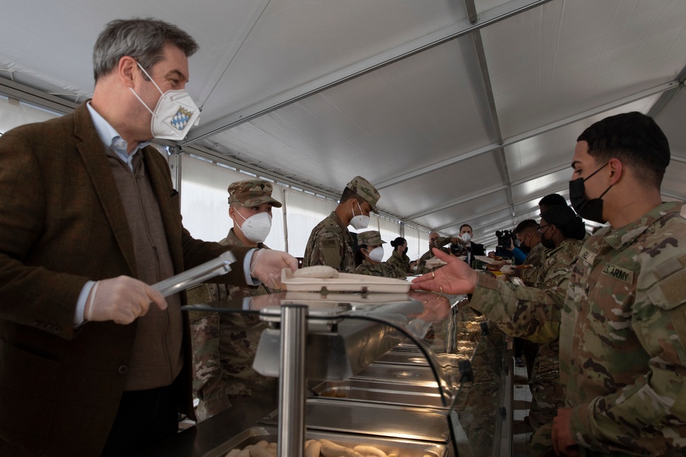The Minister President of Bavaria, Markus Soeder, serves Weisswurst and pretzels to American Soldiers