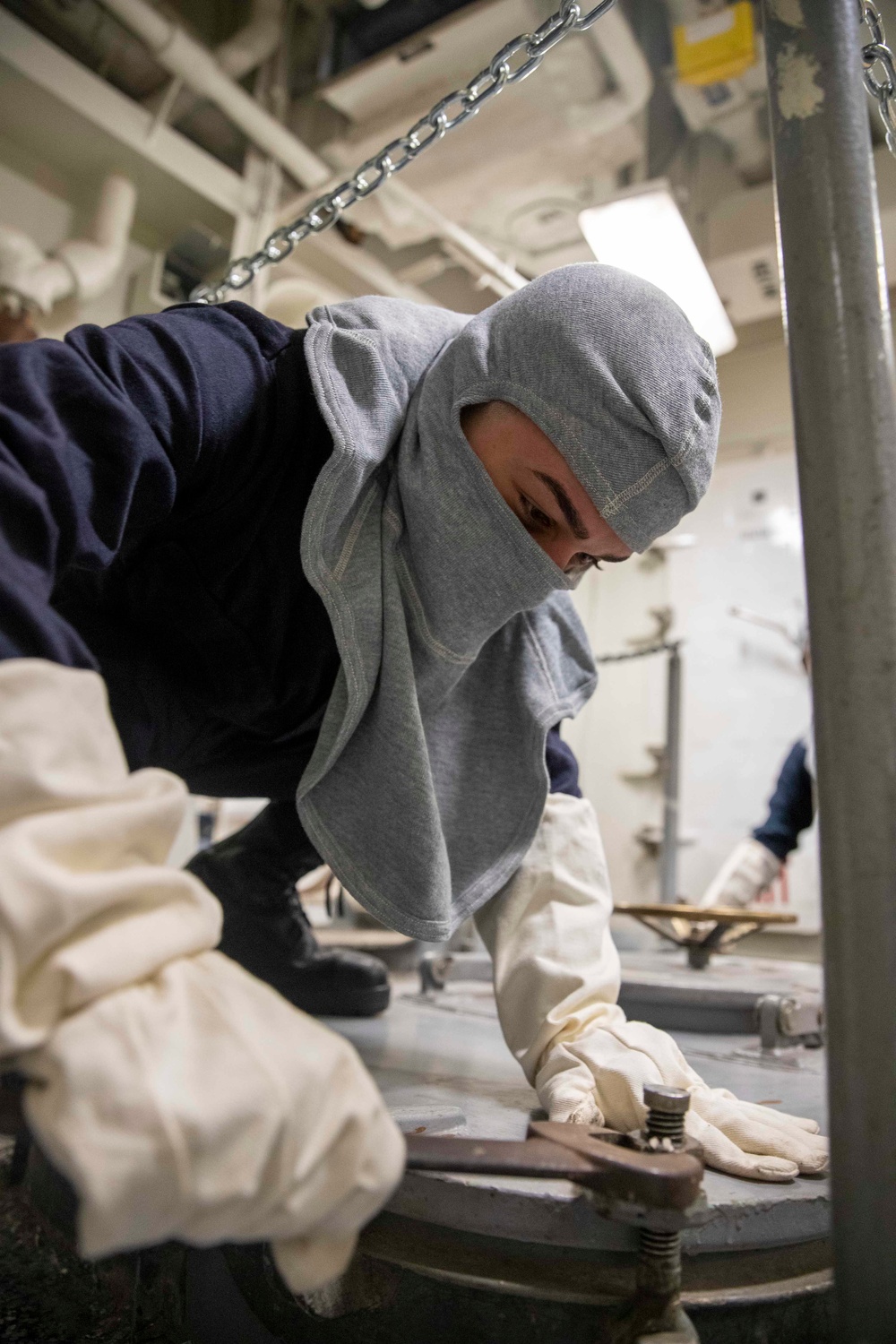 Seaman Isaiah M. Crespo, from Tampa Florida, assigned to deck department aboard the Nimitz-class aircraft carrier USS George Washington (CVN 73), closes a hatch with a dogging wrench during general quarters drill.