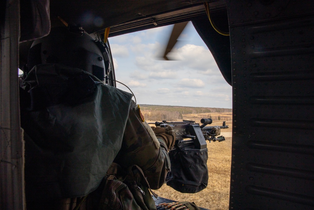 A U.S. Army Soldier from Alpha Company 2nd Battalion, 227th Aviation Regiment, 1st Air Cavalry fires an M240H from a UH-60 Blackhawk at Grafenwoehr Training Area, Germany on March 16, 2022